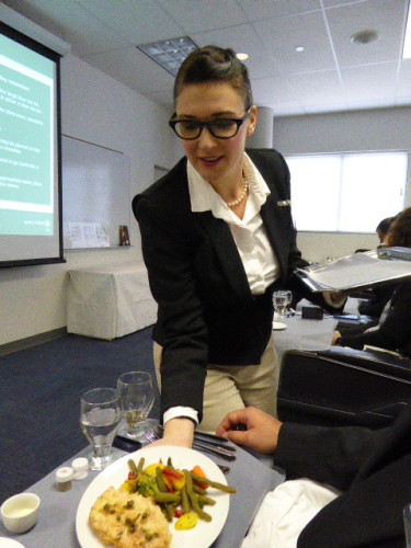 United flight attendant trainee practicing serving a premium class meal