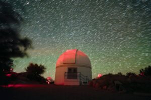 The night sky above Kitt Peak National Observatory, the Burrell Schmidt Telescope is shown here.